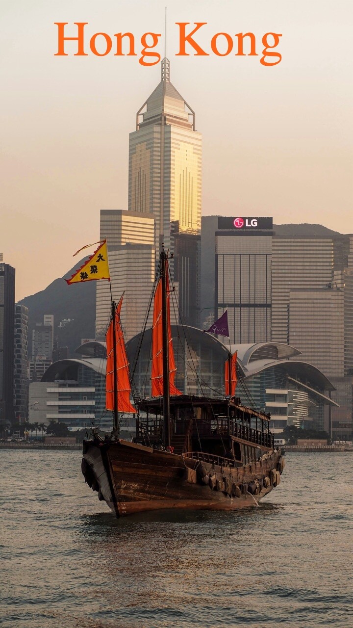 Hong Kong harbour at dusk with a red-sail junk passing the Wan Chai skyline, Bizwholistic's home base